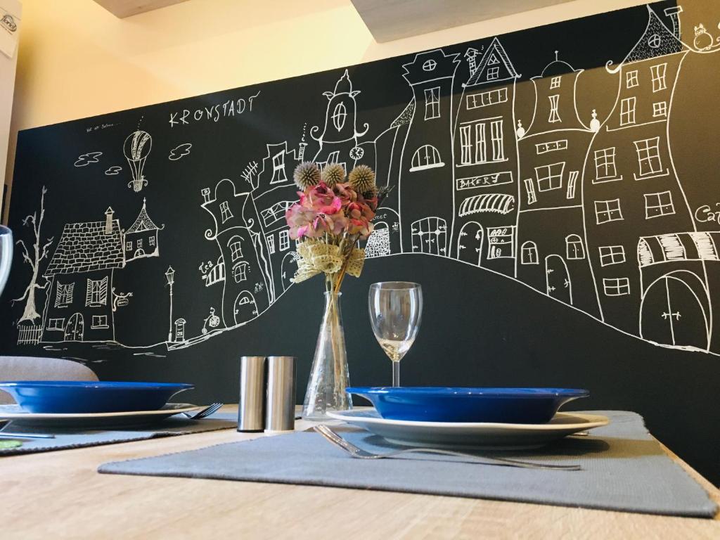 uma mesa com duas placas e um quadro-negro com desenhos em Marge’s cosy Old Town Nest em Brasov