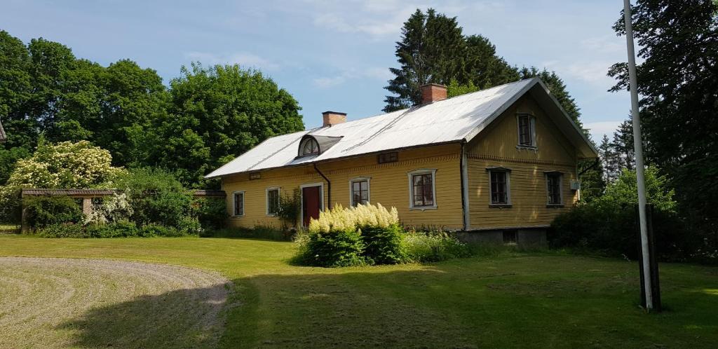 une ancienne maison avec un toit en étain sur un champ dans l'établissement Magderuds gårdshus, à Beateberg