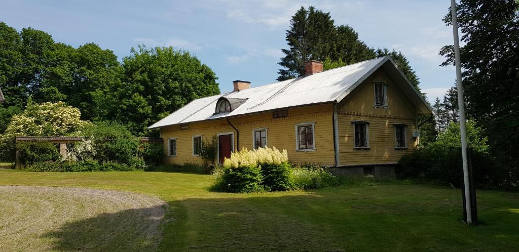 una casa vieja con un techo de estaño en un campo en Magderuds gårdshus, en Beateberg