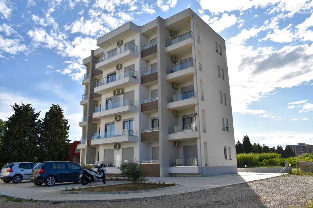 a white building with cars parked in front of it at Lux Kalimera Apartments in Ulcinj