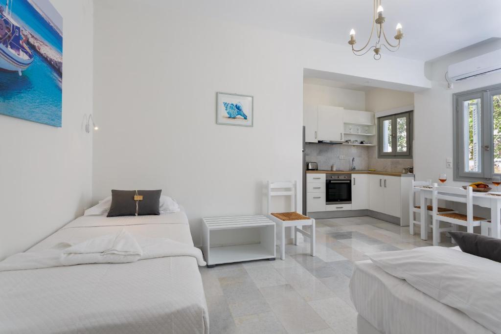 Heart of Paros Apartments في كامبوس باروس: غرفة بيضاء بسريرين ومطبخ