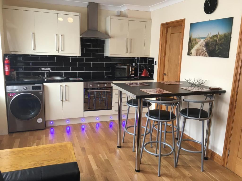 a kitchen with white cabinets and a island with bar stools at Ground floor 2 bed apartment in central location with private access to 7 miles of sandy beach (sleeps 4) in Brean