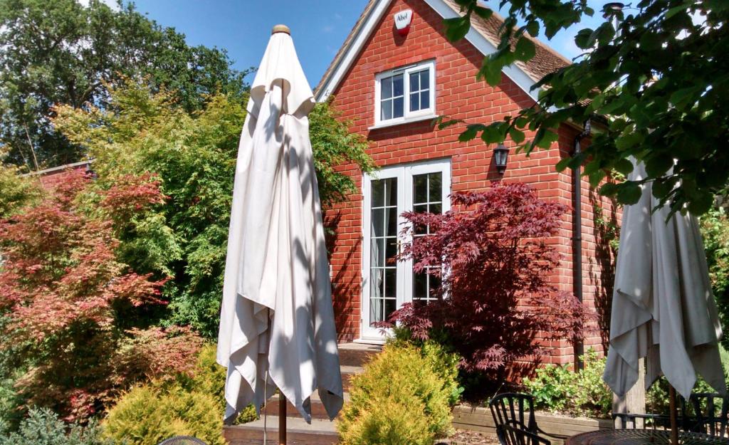 two white umbrellas in front of a brick house at Criddlestyle Cottage - 5 bedroom New Forest Holiday Home in Fordingbridge