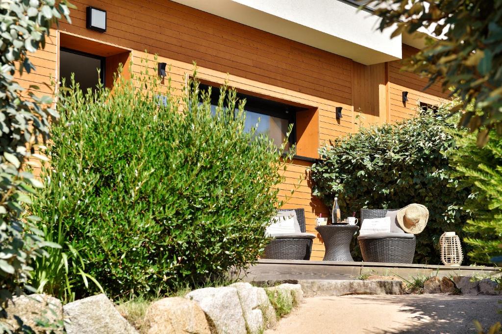 a house with chairs and a bush in front of it at Résidence & Hotel U Livanti ECOLABEL in Propriano
