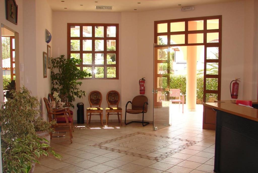 a living room with chairs and tables and windows at Georges Estates Hotel in Stoupa
