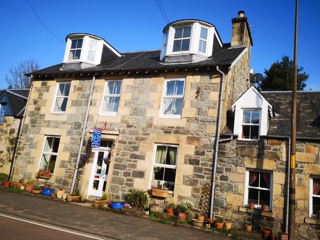 an old stone house with three windows on a street at Rosebank House Bed & Breakfast in Strathyre