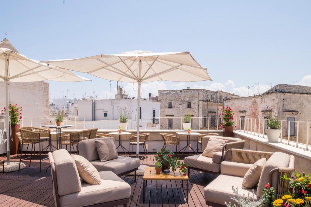un toit-terrasse avec des canapés, des tables et des parasols dans l'établissement Sei Stelle Mama, à Polignano a Mare