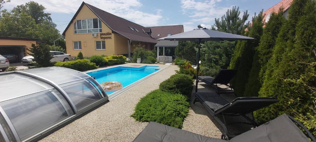 einen Hinterhof mit Pool und Sonnenschirm in der Unterkunft Penzión Veperec in Hokovce