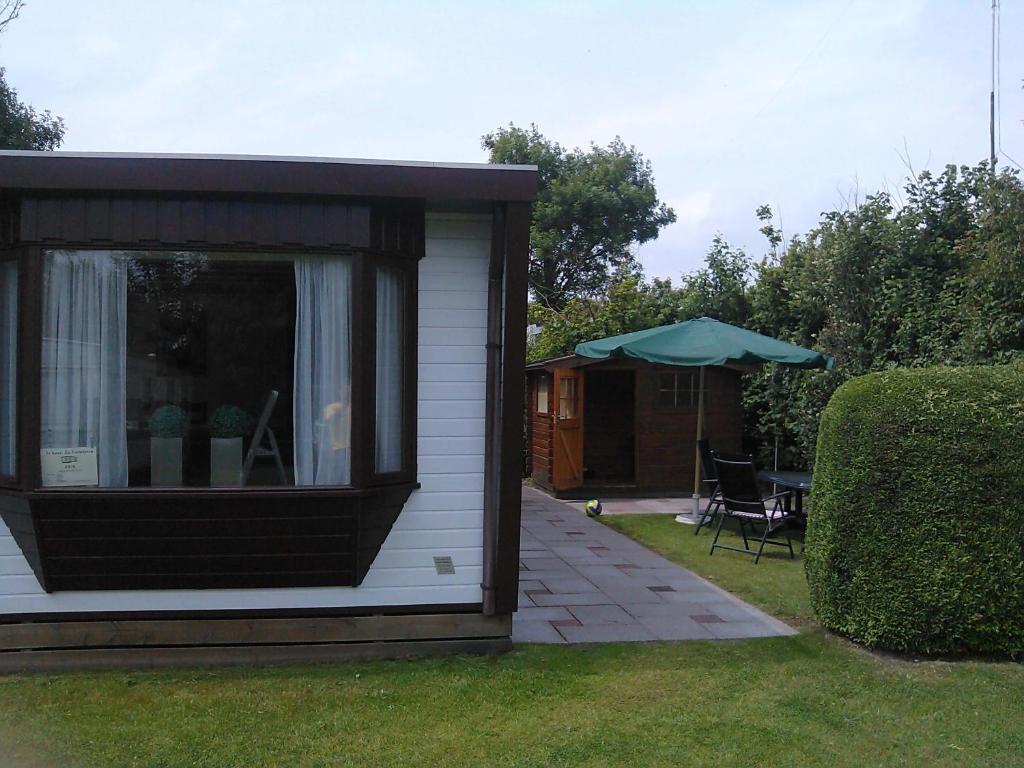 een schuur met een tafel en een paraplu in een tuin bij Stacaravanverhuur KR00N chalet FF-5 in Workum