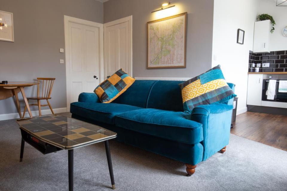 a blue couch in a living room with a table at High Terrace Apartment in Boat of Garten