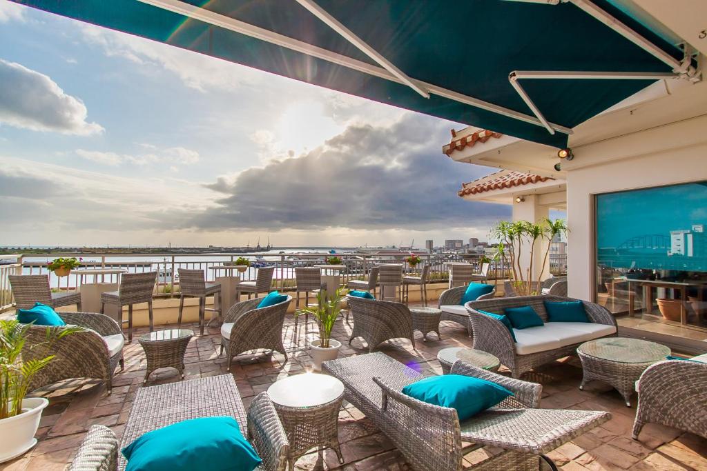 eine Terrasse mit Stühlen und Tischen und Blick auf das Wasser in der Unterkunft Hotel East China Sea in Ishigaki-jima