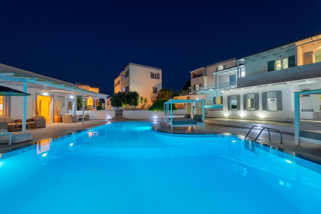 a large swimming pool in front of a building at night at Aegean Paradiso Vacation Club in Azolimnos