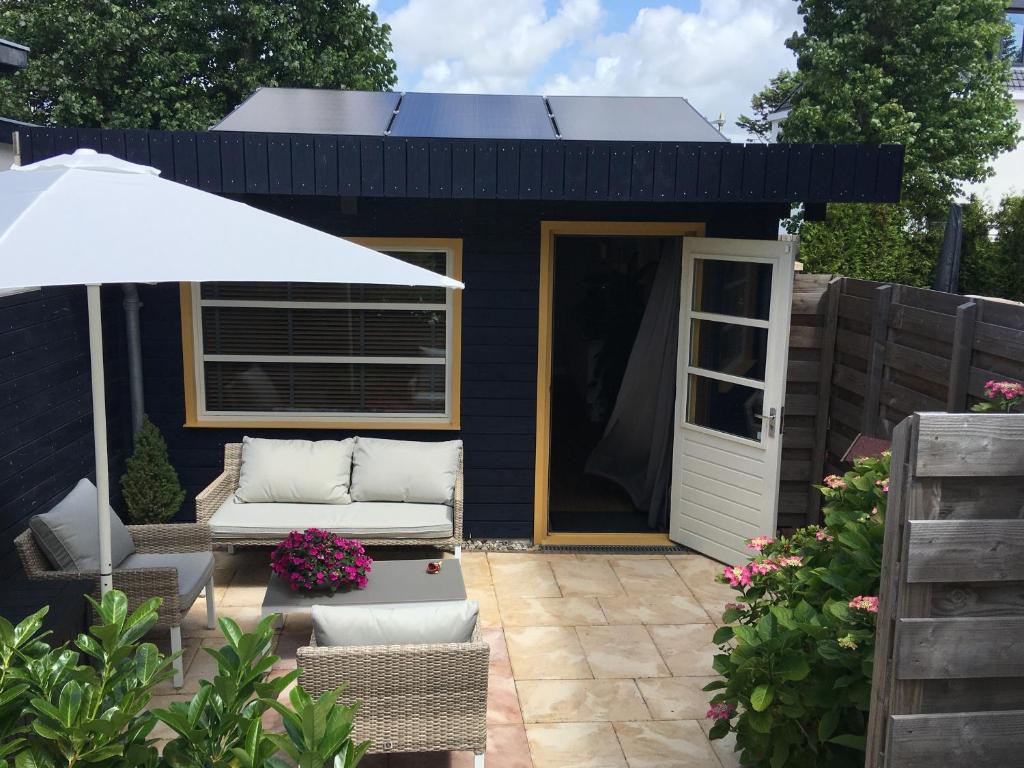 a black shed with a couch and an umbrella at Annadora Beach House - Free Parking in Zandvoort