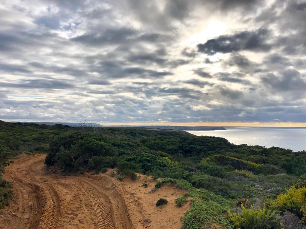 a dirt road next to a body of water at Hortas do Rio - Casa de Campo in Carrapateira