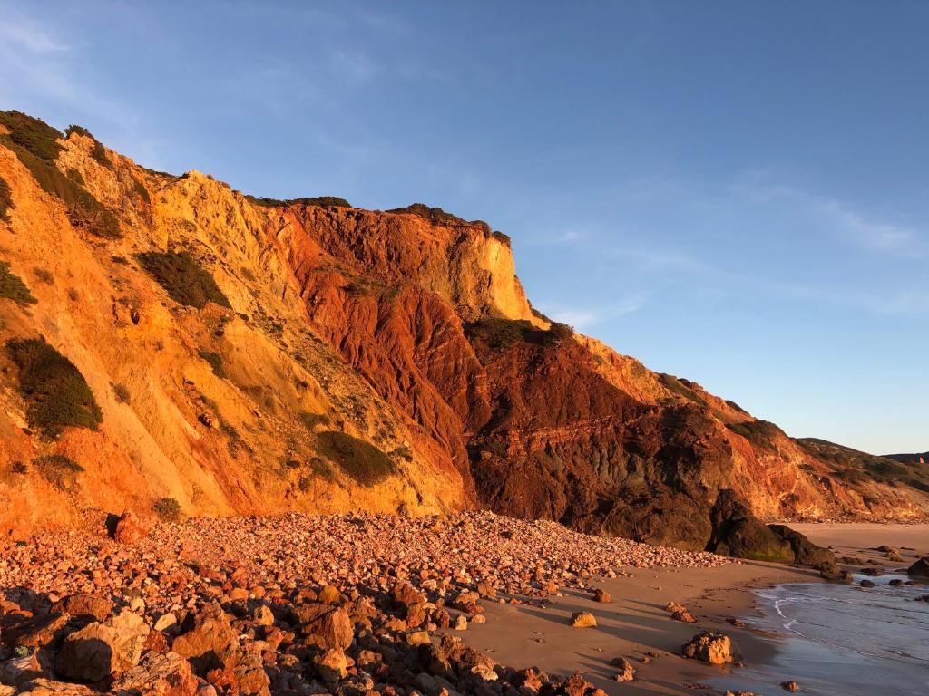a beach with rocks and a cliff at Hortas do Rio - Casa de Campo in Carrapateira