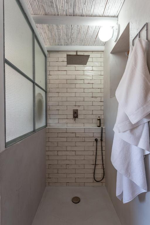 a bathroom with a shower with a white brick wall at Hortas do Rio - Casa de Campo in Carrapateira