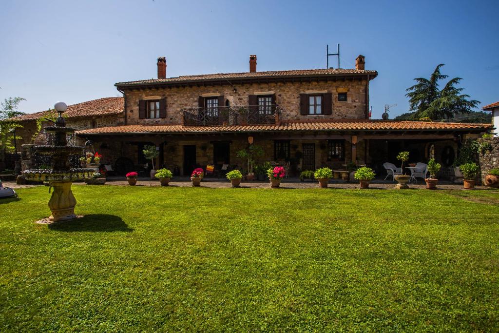 una casa grande con césped delante en Posada Real La Montañesa en Los Corrales de Buelna