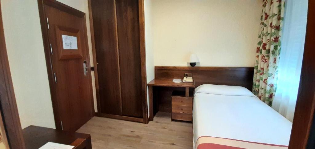 a small room with a bed and a desk at Hotel Urogallo in Vielha