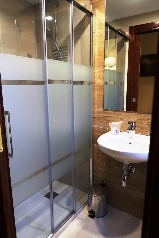 a bathroom with a glass shower and a sink at Hotel Urogallo in Vielha