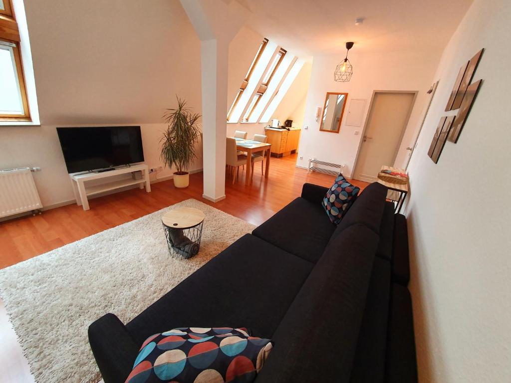 ein Wohnzimmer mit einem schwarzen Sofa und einem TV in der Unterkunft Zentrales Dachgeschoss-Apartment Bielefeld in Bielefeld