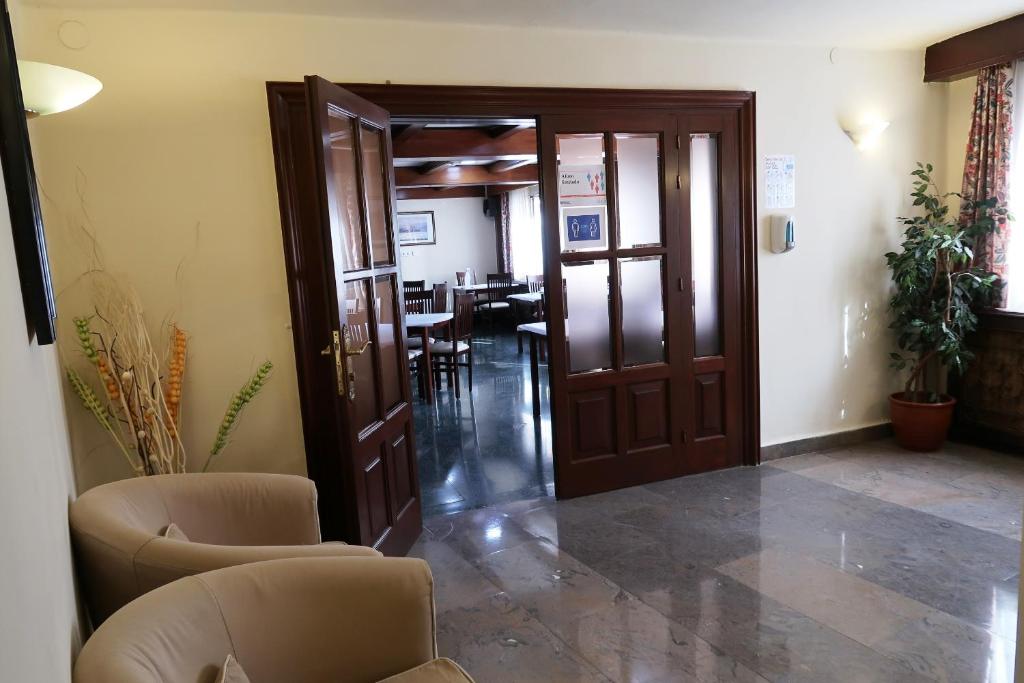 a lobby with two chairs and a door and a table at Hotel Urogallo in Vielha