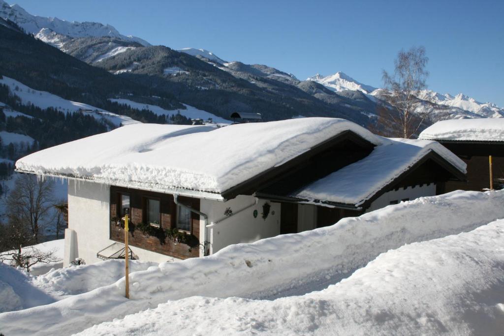 ein schneebedecktes Haus mit Bergen im Hintergrund in der Unterkunft Schernthaner in Taxenbach