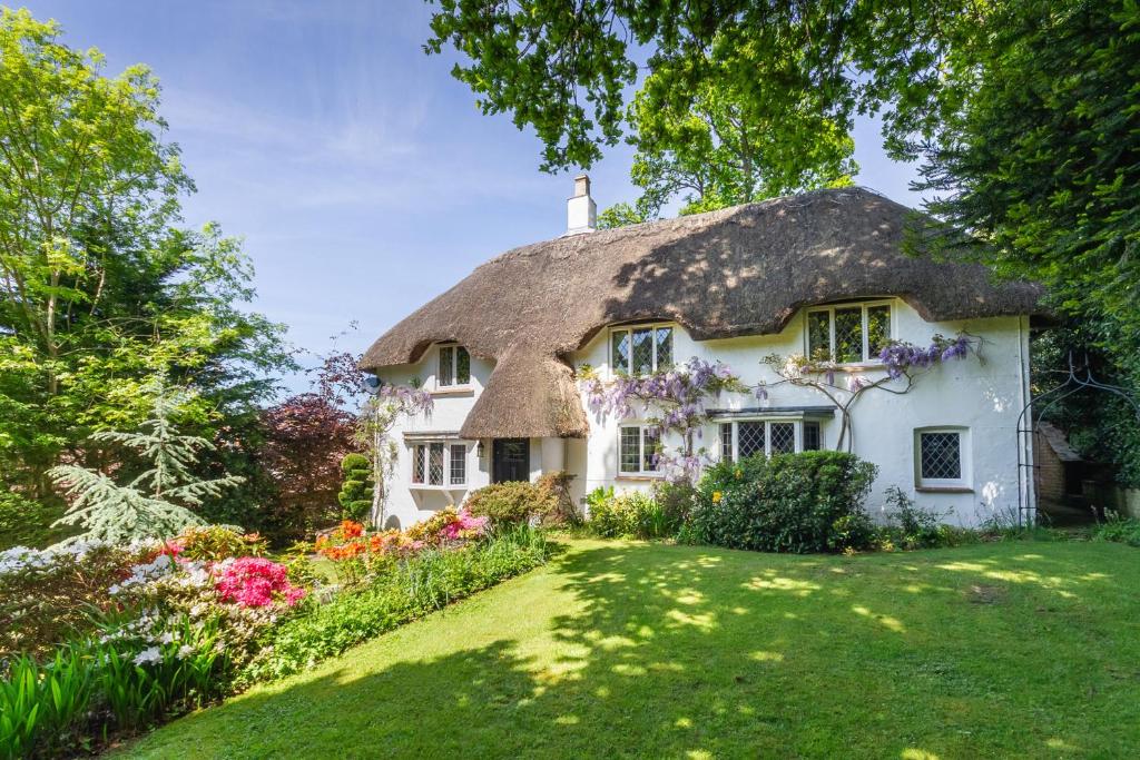 a thatched cottage with a garden in front of it at Forest Drove Cottage · Idyllic New Forest 6 Bedroom Thatched Cottage in Ringwood
