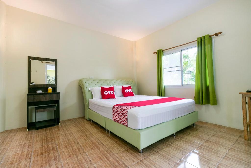 Schlafzimmer mit einem Bett mit roten Kissen und einem Spiegel in der Unterkunft OYO 953 Tawan Resort in Cha-am