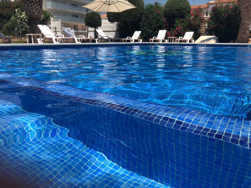 una gran piscina azul con sillas y sombrilla en Hotel Plaza Miami - Sólo Adultos, en Miami Platja