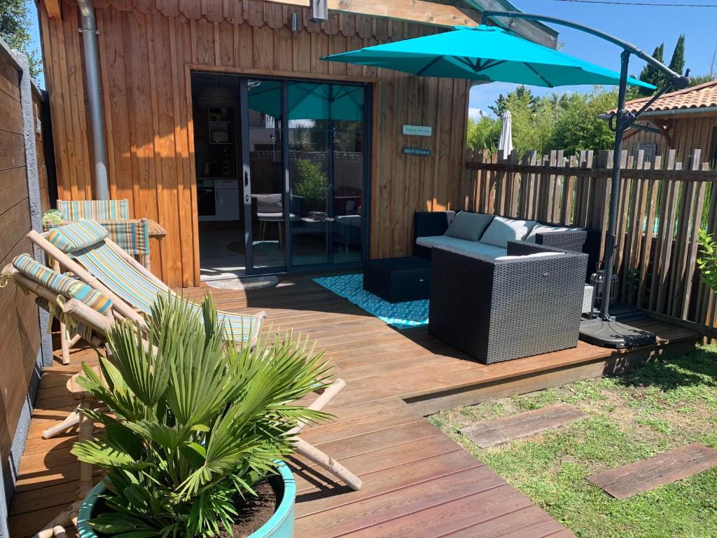 een houten terras met een bank en een parasol bij La cabane 62 in La Teste-de-Buch