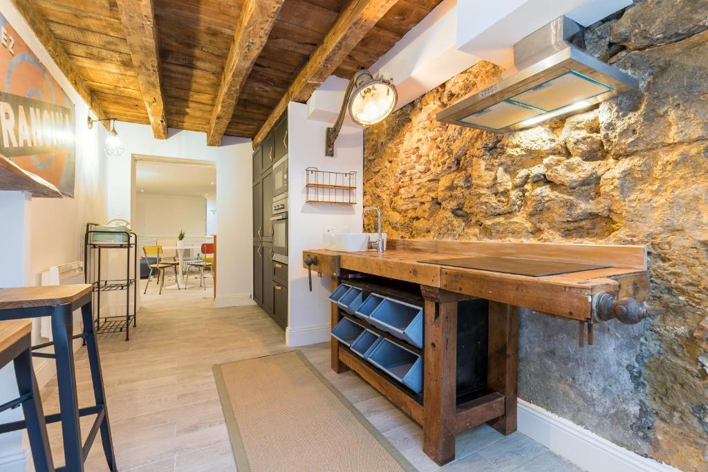 une cuisine avec un comptoir et un mur en pierre dans l'établissement Les Deux Clefs, à Mont-de-Marsan