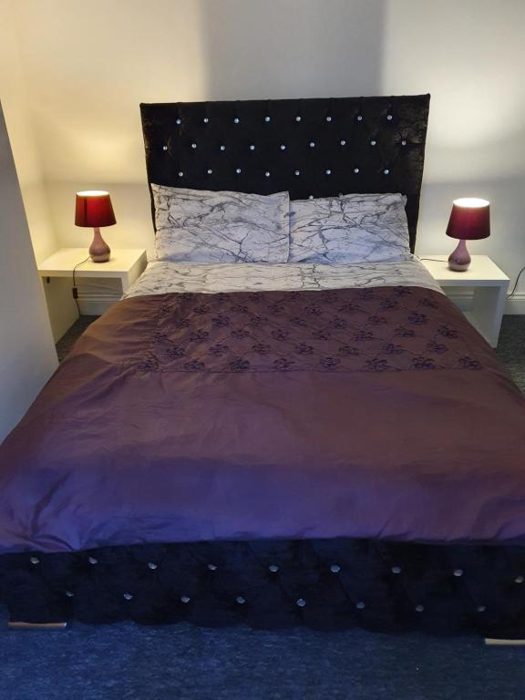 a bedroom with a large bed with two lamps at Waterloo apartment in Middlesbrough