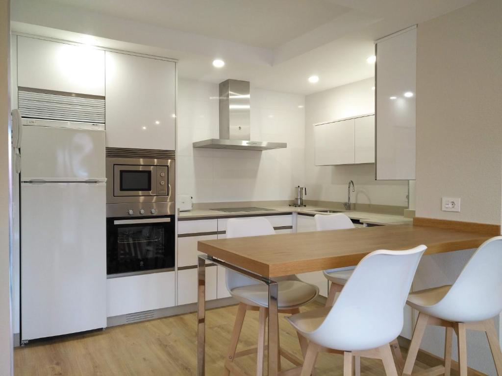 a kitchen with a wooden table and white chairs at Apartamento El Manin in Villaviciosa