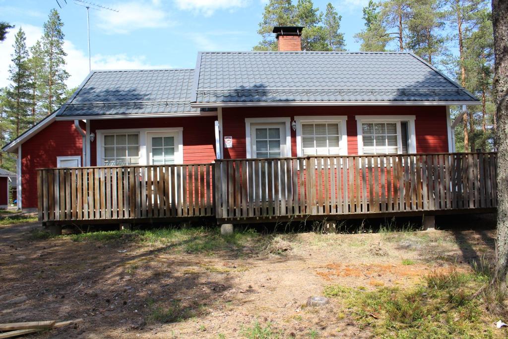 a small red house with a wooden fence at Veikkola Hiekkasärkät in Kalajoki