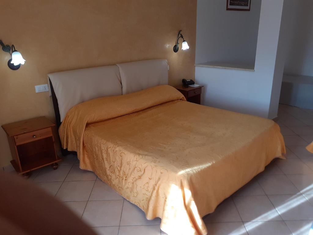a bedroom with a bed with a orange bedspread at H- Rooms La Darsena in San Vito lo Capo