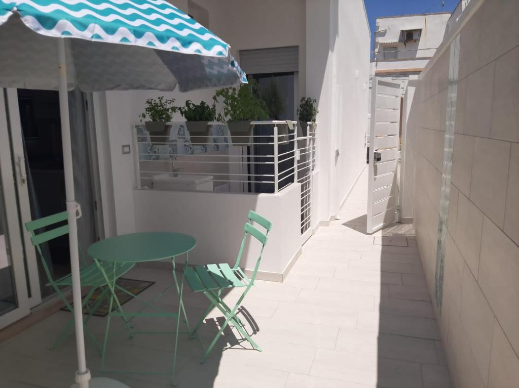 un tavolo con sedie e un ombrellone su un balcone di GIOANTHONY monolocale a Porto Cesareo