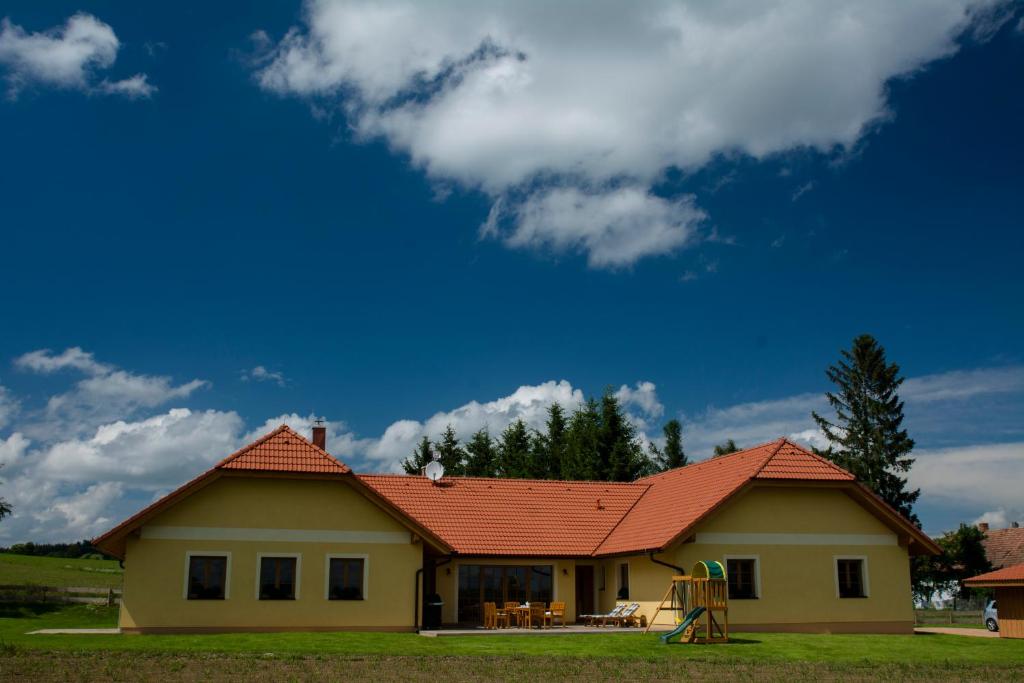 une maison avec un toit orange sur un champ dans l'établissement Apartmány v Pošumaví, à Stachy