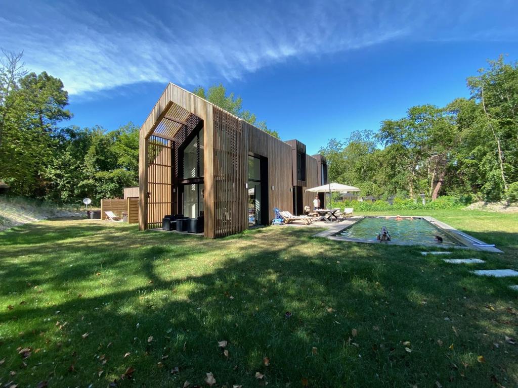 une maison en bois dans un champ avec une piscine dans l'établissement Les Tchanquées, à Le Touquet-Paris-Plage