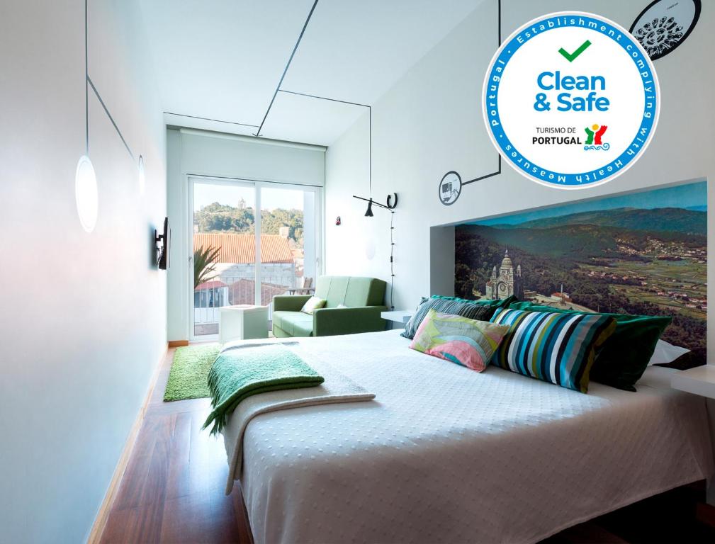 a white bedroom with a large bed and a chair at Pensao O Laranjeira in Viana do Castelo