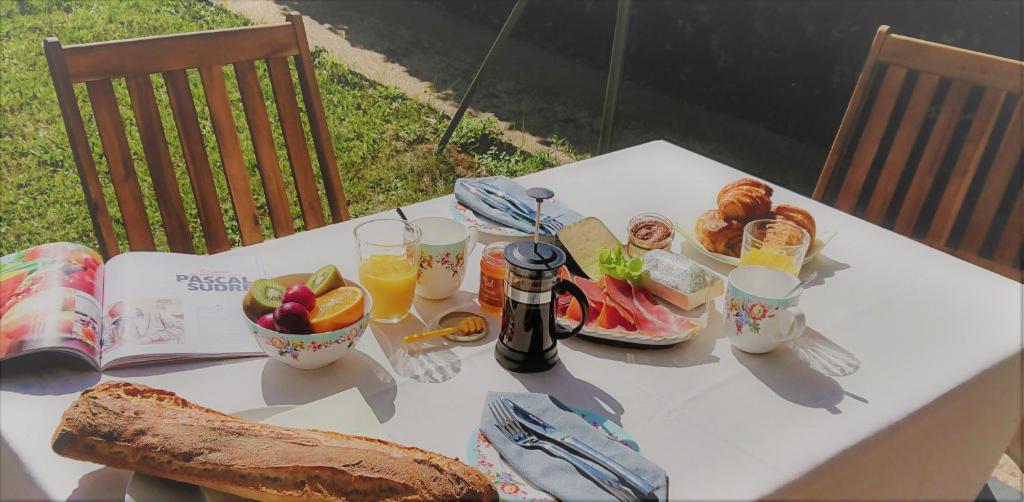 a white table with food and drinks and a book at Fleurs de Cosmos in Albi