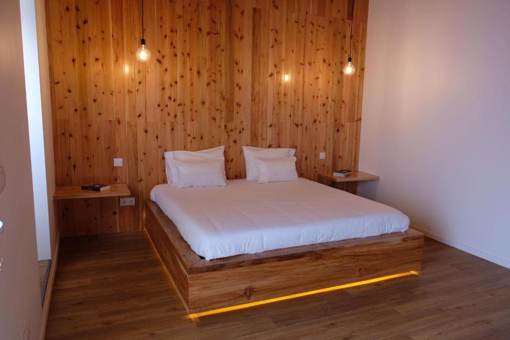 Estúdio Azul في بونتا ديلغادا: غرفة نوم بسرير وجدران خشبية وارضيات خشبية