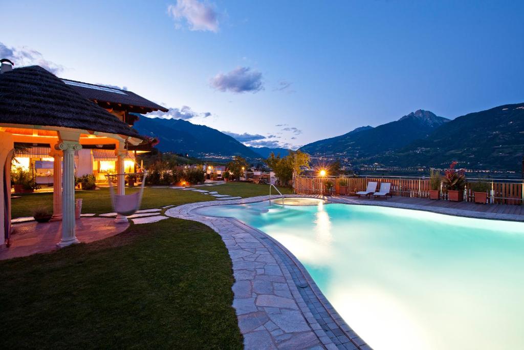 una piscina in un cortile con montagne di notte di Hotel & Appartement Valtnaungut a Cermes