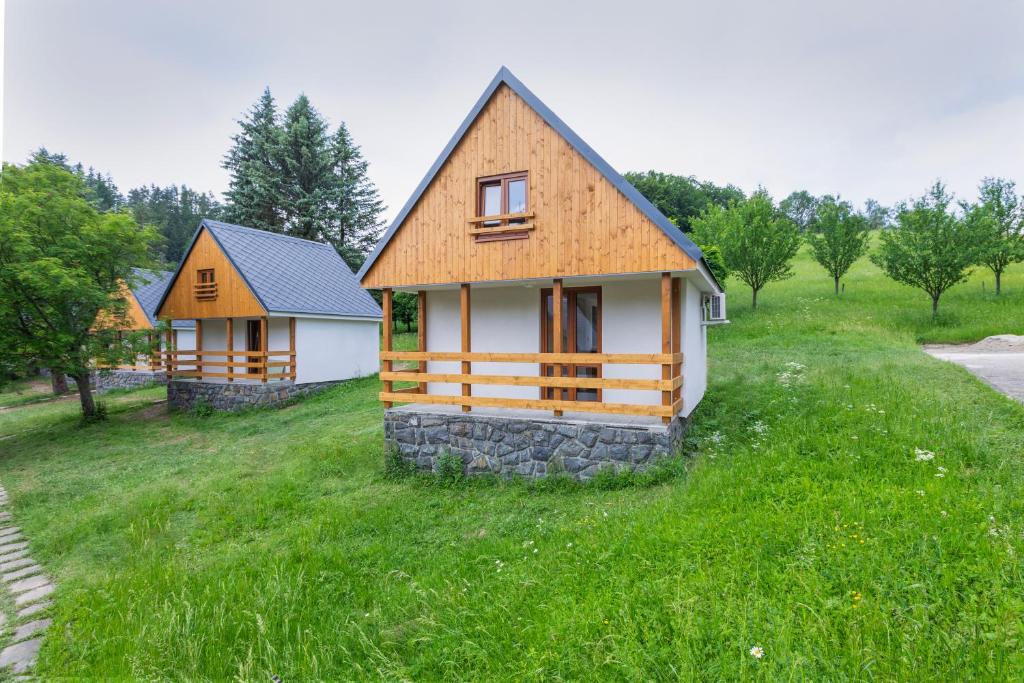 a small house on a grassy hill with trees at Hotel Rusava chaty in Rusava