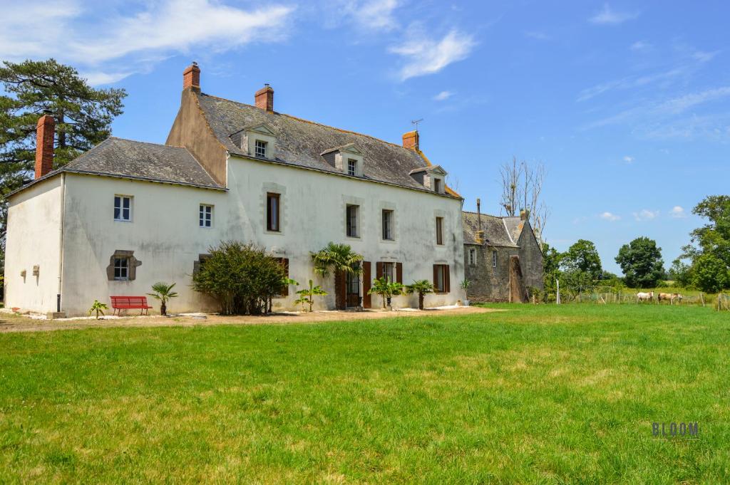 una casa vieja con un campo verde delante de ella en Manoir de L'Aisnerie en Saint-Herblain