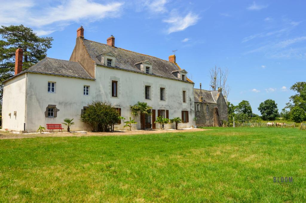 une vieille maison avec un champ vert devant elle dans l'établissement Manoir de L'Aisnerie, à Saint-Herblain