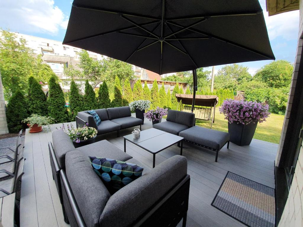 eine Terrasse mit Sofas, einem Tisch und einem Sonnenschirm in der Unterkunft Elly House in Haapsalu