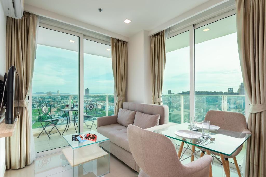 a living room with a table and chairs and large windows at Rare Panoramic Sea, City & Mountain Views - XXL Balcony - Free Fast WIFI - Pool - City Garden Tower 2317 in Pattaya South