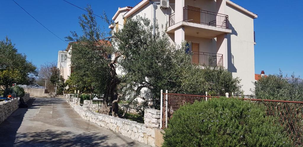 a white building with a fence next to a street at Apartments Jelica in Slatine