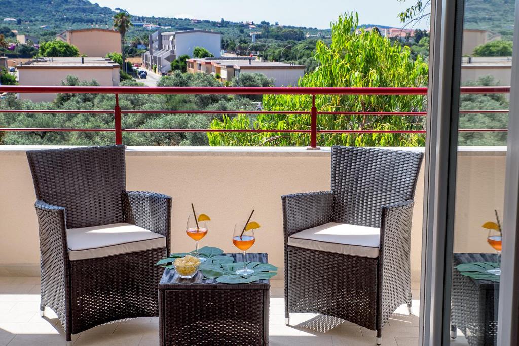 a balcony with two chairs and a table with wine glasses at Marco's House in Alghero