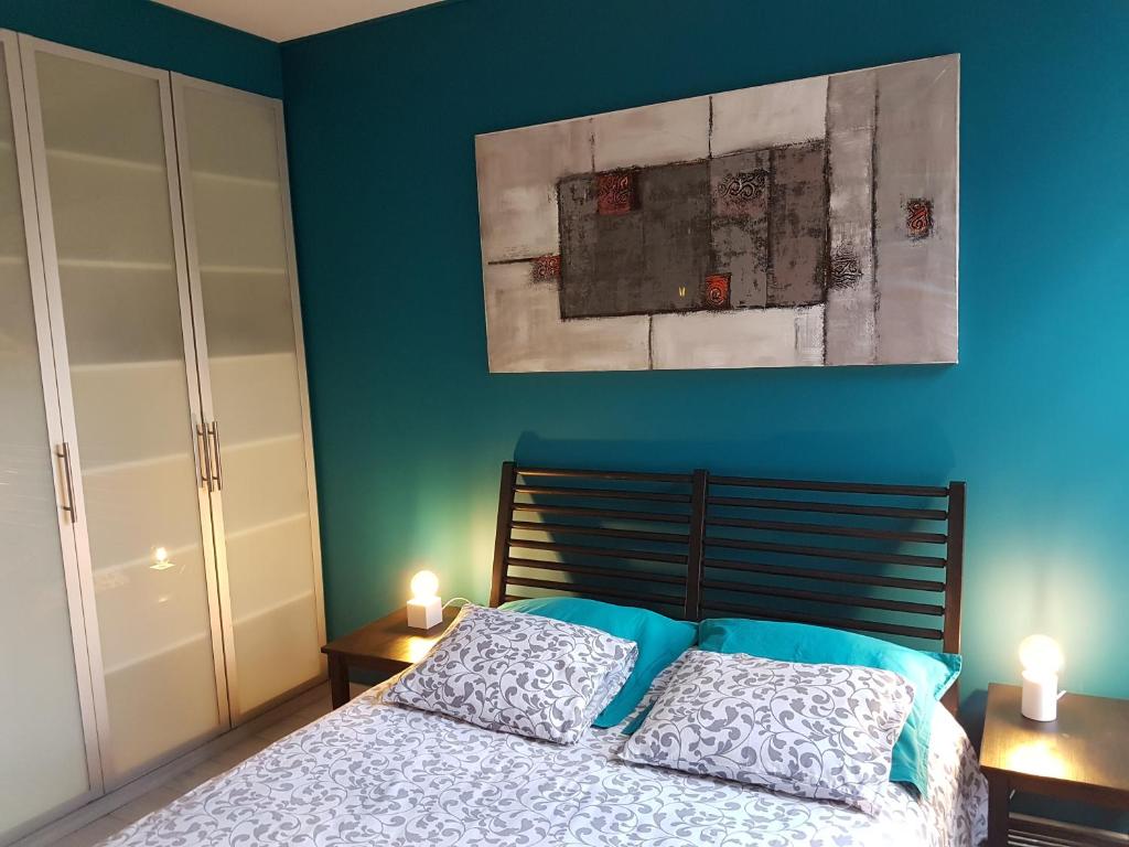 een slaapkamer met blauwe muren en een bed met 2 kussens bij B&B Brigitte & Alain in Brussel